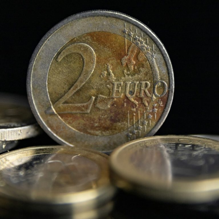 Monedas de euro con una de dos euros en primer plano sobre un fondo oscuro que simboliza ahorro