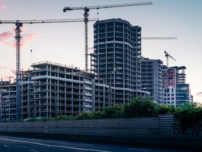 Edificios en construcción rodeados de grúas bajo un cielo al atardecer que necesitaran hipotecas