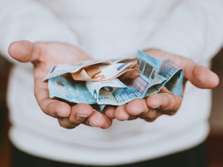 MRP ASESORES Manos sosteniendo billetes arrugados de diferentes denominaciones procedente de su ahorro