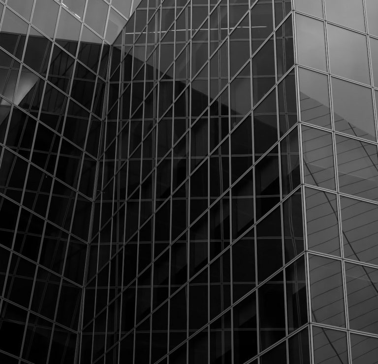 Edificio moderno con fachadas de cristal y reflejos en blanco y negro.